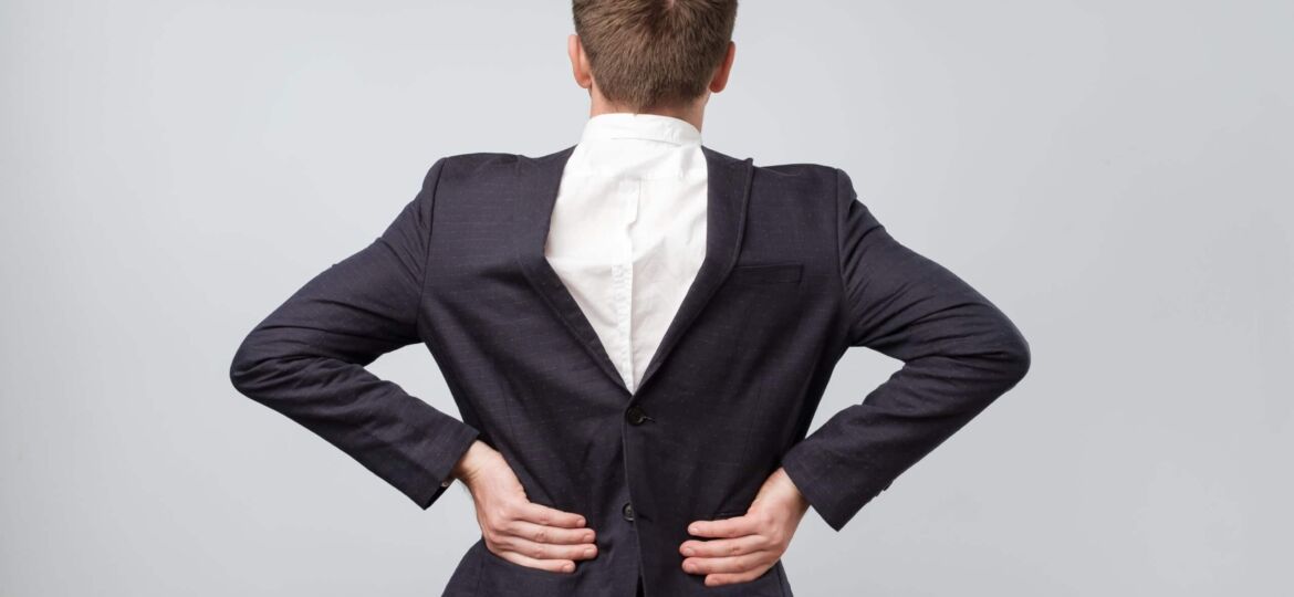 Studio shot of a mature caucasian man wearing his suit on backwards, gray background