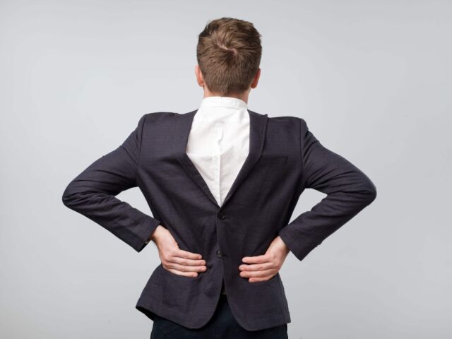 Studio shot of a mature caucasian man wearing his suit on backwards, gray background